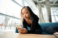 Young sad asian female IT employee using smartphone on sofa at table in office Royalty Free Stock Photo