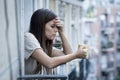 Young sad beautiful woman suffering depression looking worried and wasted on home balcony