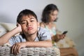 Young sad and bored Asian child at home couch feeling frustrated and unattended while mother networking on mobile phone as Royalty Free Stock Photo