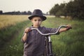 A young, sad boy dressed in a retro style, runs an old bicycle in the countryside. Royalty Free Stock Photo