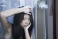 Young sad and depressed Asian Chinese woman looking thoughtful through window glass suffering pain and depression in sadness conce Royalty Free Stock Photo