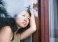 Young sad and depressed Asian Chinese woman looking thoughtful through window glass suffering pain and depression in sadness conce Royalty Free Stock Photo