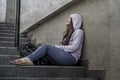 Depressed Asian Japanese student woman or bullied teenager girl sitting outdoors on street staircase victim of bullying feeling Royalty Free Stock Photo