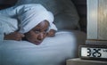 Young sad depressed black afro American woman awake on bed sleepless suffering insomnia sleeping disorder anxiety problem with ala Royalty Free Stock Photo