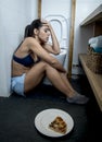 Young sad and depressed bulimic woman feeling sick guilty after vomiting pizza in WC toilet