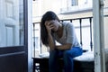 Desperate Latin woman sitting at home balcony looking destroyed and depressed suffering depression Royalty Free Stock Photo