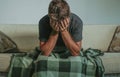 Young sad and desperate man at home sitting at sofa couch covering face with hands crying suffering depression and stress feeling Royalty Free Stock Photo