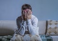 Young sad and desperate man at home sitting at sofa couch holding head with hands suffering depression and stress worried about pr Royalty Free Stock Photo