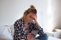 Young sad emotional girl seated on bed indoor Royalty Free Stock Photo