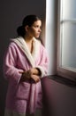 Young sad girl, cancer patient looking through hospital window