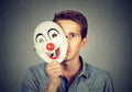 Young sad man hiding behind happy clown mask Royalty Free Stock Photo