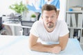 Young sad man lying on couch in front of doctor proctologist in clinic