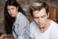 Young sad man thinking of betrayal, upset girlfriend at backgrou