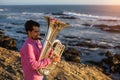 Young sad musician playing the trumpet on the ocean coast. Royalty Free Stock Photo