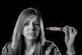 Young sad pregnant woman or female teenager scared and shocked holding pregnancy test positive result