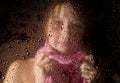 Young sad woman portrait behind the window in the rain with rain drops on it Royalty Free Stock Photo