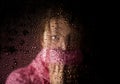 Young sad woman portrait behind the window in the rain with rain drops on it Royalty Free Stock Photo