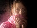 Young sad woman portrait behind the window in the rain with rain drops on it Royalty Free Stock Photo