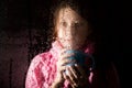 Young sad woman portrait behind the window in the rain with rain drops on it. girl holding a cup of hot drink Royalty Free Stock Photo