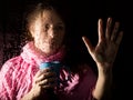 Young sad woman portrait behind the window in the rain with rain drops on it. girl holding a cup of hot drink Royalty Free Stock Photo