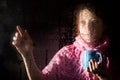 Young sad woman portrait behind the window in the rain with rain drops on it. girl holding a cup of hot drink Royalty Free Stock Photo