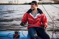 Young sailor in cap holds and moves ropes with both hands. He is happy and smiling Young man is preparing yacht for Royalty Free Stock Photo