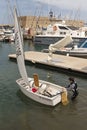 Young sailor climbs aboard a dingy for a sailing lesson.