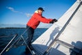 Young sailor in sunglasses and cap holds and moves ropes with both hands. He is calm and concentrated. Young man is Royalty Free Stock Photo