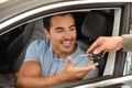 Young salesman giving car key to in modern auto dealership, closeup