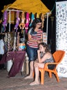 A young saleswoman weaves another young girl into the hair just sold ornaments in the evening on the waterfront in the city of Nah