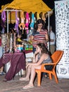 A young saleswoman weaves another young girl into the hair just sold ornaments in the evening on the waterfront in the city of Nah