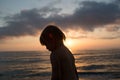 Young sand dirty child girl silhouette looking away beach shore. Warm sunset light. Family summer travel vacations at