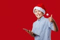 Young santa boy making the ok thumbs up gesture while holding a tablet Royalty Free Stock Photo