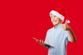 Young santa boy making the ok thumbs up gesture while holding a tablet Royalty Free Stock Photo