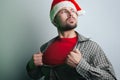 Young Santa Claus rips his shirt on his chest like a superhero. the man in the Santa hat Royalty Free Stock Photo