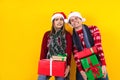 Young Santa latin couple friends man and woman in red sweater Christmas hat holding heavy gift boxes with gift ribbon bow on