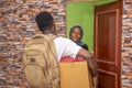 Young satisfied African female receiving a parcel from the courier