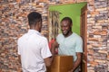 Young satisfied African male receiving a parcel from the courier