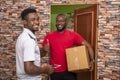 Young satisfied African male receiving a parcel from the courier