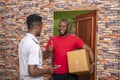 Young satisfied African male receiving a parcel from the courier