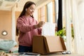 Young satisfied buyer. Happy teen girl received package, unpacking cardboard box, looking inside