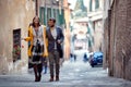 A young satisfied couple is walking the old city and chatting. Walk, rain, city, relationship