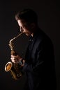 Young saxophone playing the saxophone on a dark background
