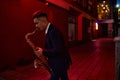 Young saxophonist plays the sax on street at night