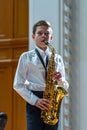 Young saxophonist on stage performs a piece.