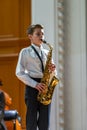 Young saxophonist on stage performs a piece.