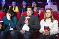 Young scared couple at the cinema watching an horror movie.