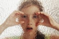 Young scared girl behind glass with her hands on it Royalty Free Stock Photo