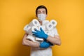 Young scared man holding many rolls of toilet paper