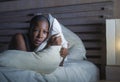 Young scared and stressed black african American woman depressed on bed upset unable to sleep suffering hangover headache feeling Royalty Free Stock Photo